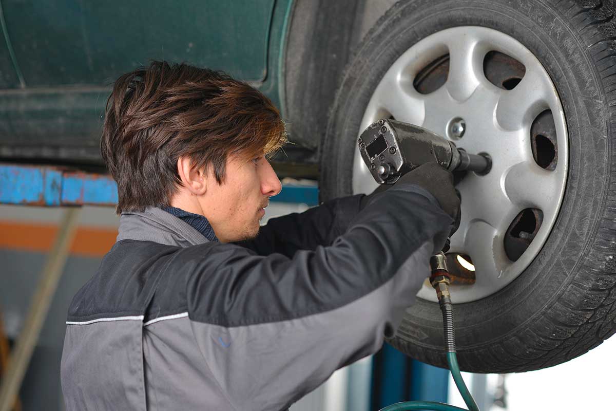 mécanicien qui change les pneus d'une voiture